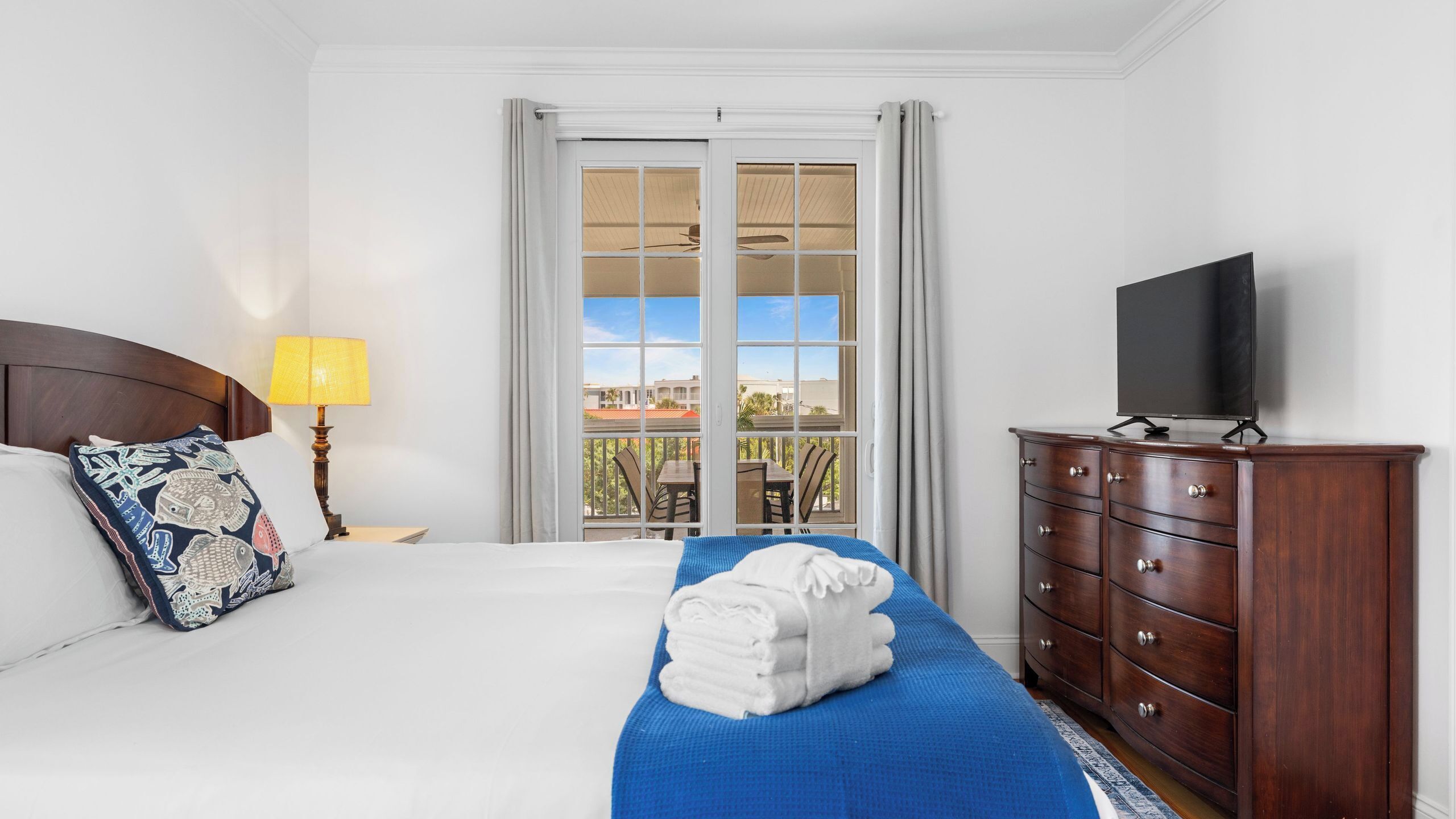 Een hotelkamer met een bed, een televisie, een dressoir en een balkon met uitzicht.