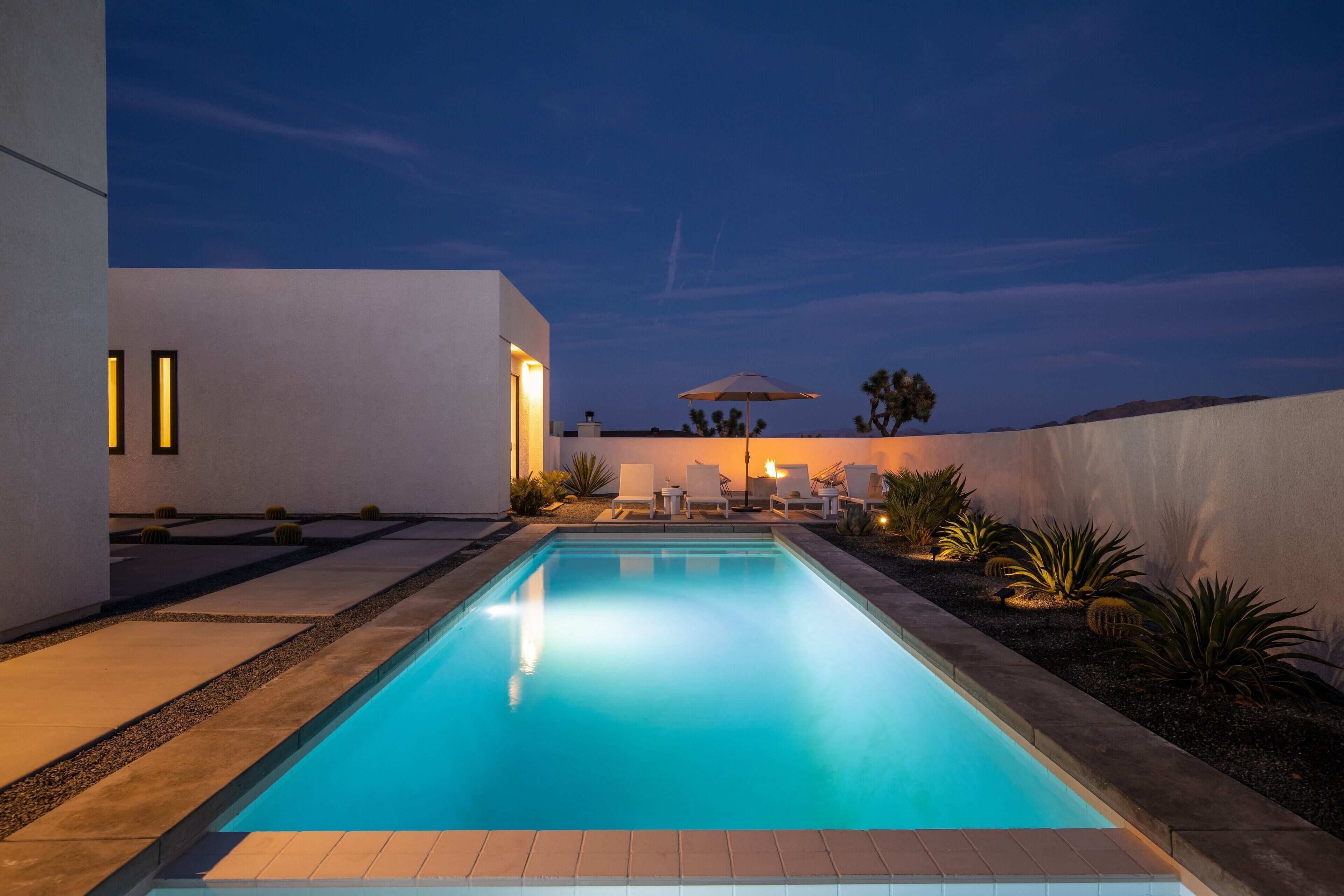 A swimming pool with a modern design, surrounded by a patio area with seating and plants.