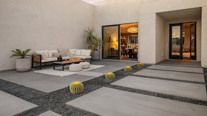 A modern outdoor patio with a sofa, coffee table, and potted plants. - Aria by Avantstay Spectacular & Secluded Desert Oasis w/ Pool (Yucca Valley)
