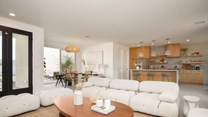 A modern living room with a sofa, a coffee table, and a dining area with a table and chairs. - Aria by Avantstay Spectacular & Secluded Desert Oasis w/ Pool (Yucca Valley)