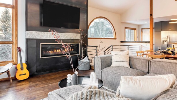 A modern living room with a fireplace, a sofa, a coffee table, and a guitar.