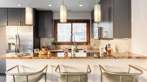 A modern kitchen with a central island, stainless steel appliances, pendant lighting, and a view through a window. - Pandora by Avantstay Modern Mountain Escape in Great Location @ Entrance of Bear Creek Trail (Telluride)