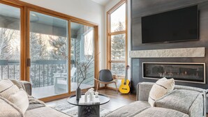 A modern living room with a fireplace, large windows, and a balcony.