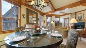 A dining area with a round glass table, chairs, and a fireplace.