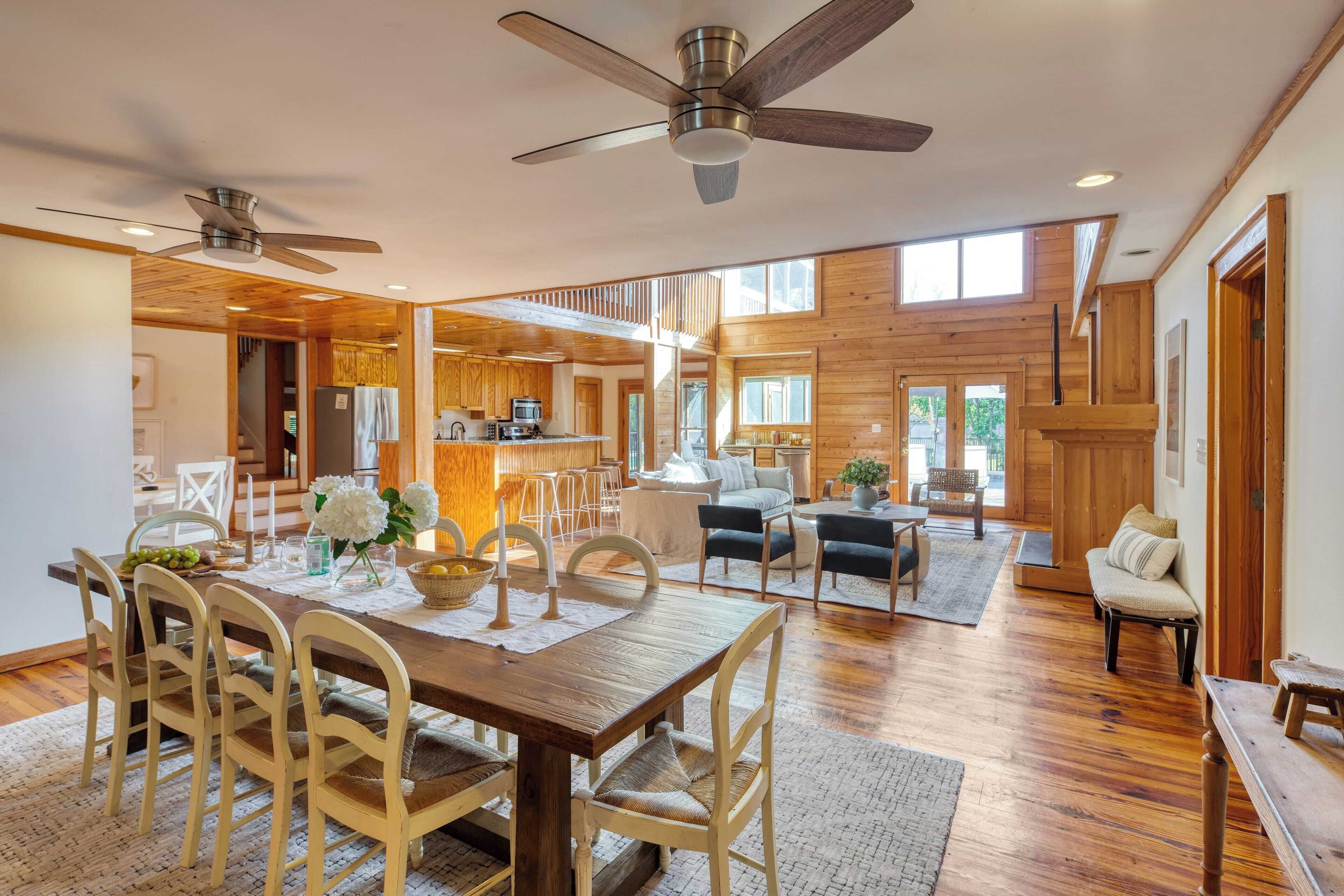 A spacious living area with a wooden dining table, chairs, and a ceiling fan.