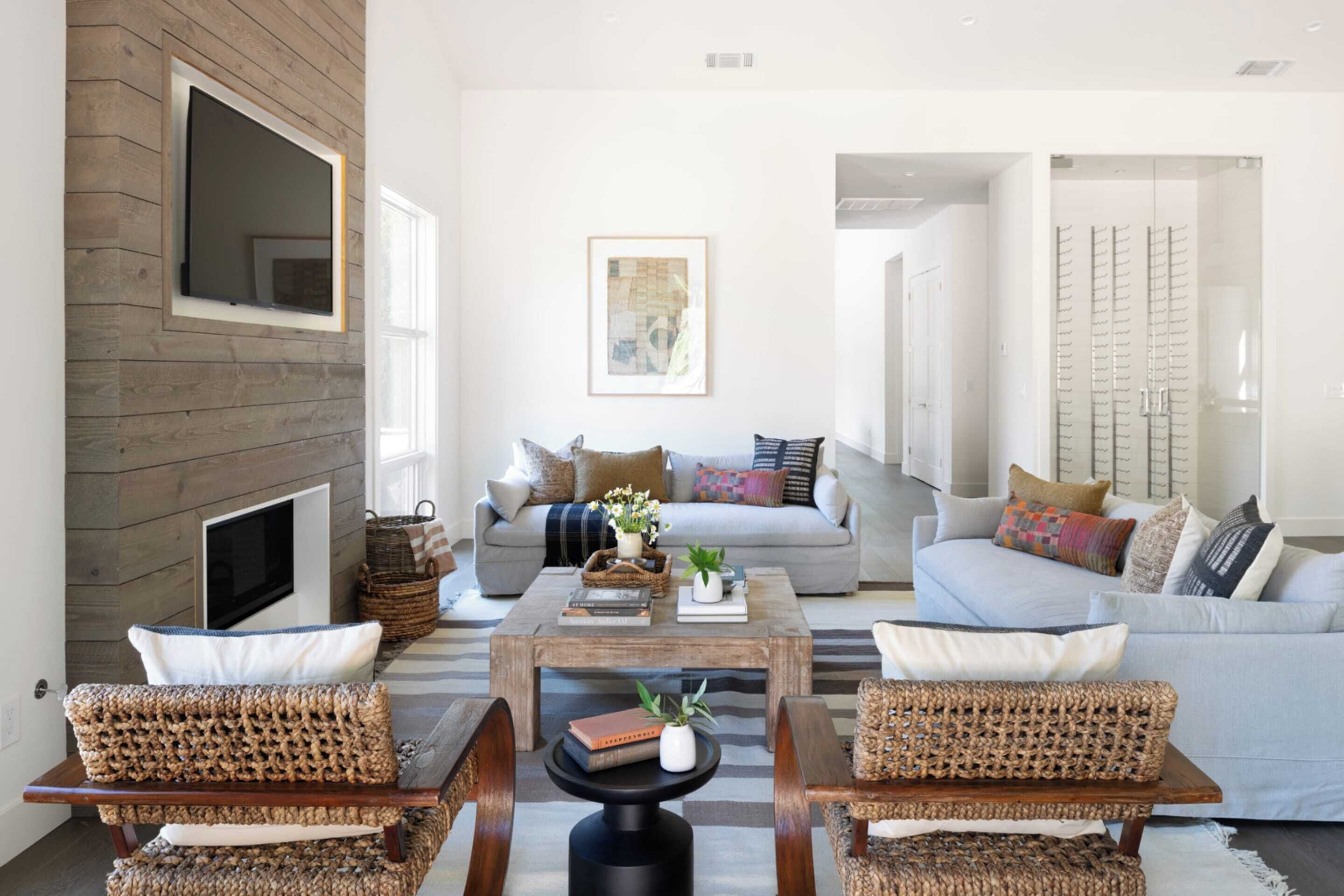 A modern living room with a fireplace, a sofa, a coffee table, and wicker chairs.