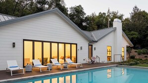 Une maison moderne dotée d’une piscine, d’une façade blanche et de grandes fenêtres.
