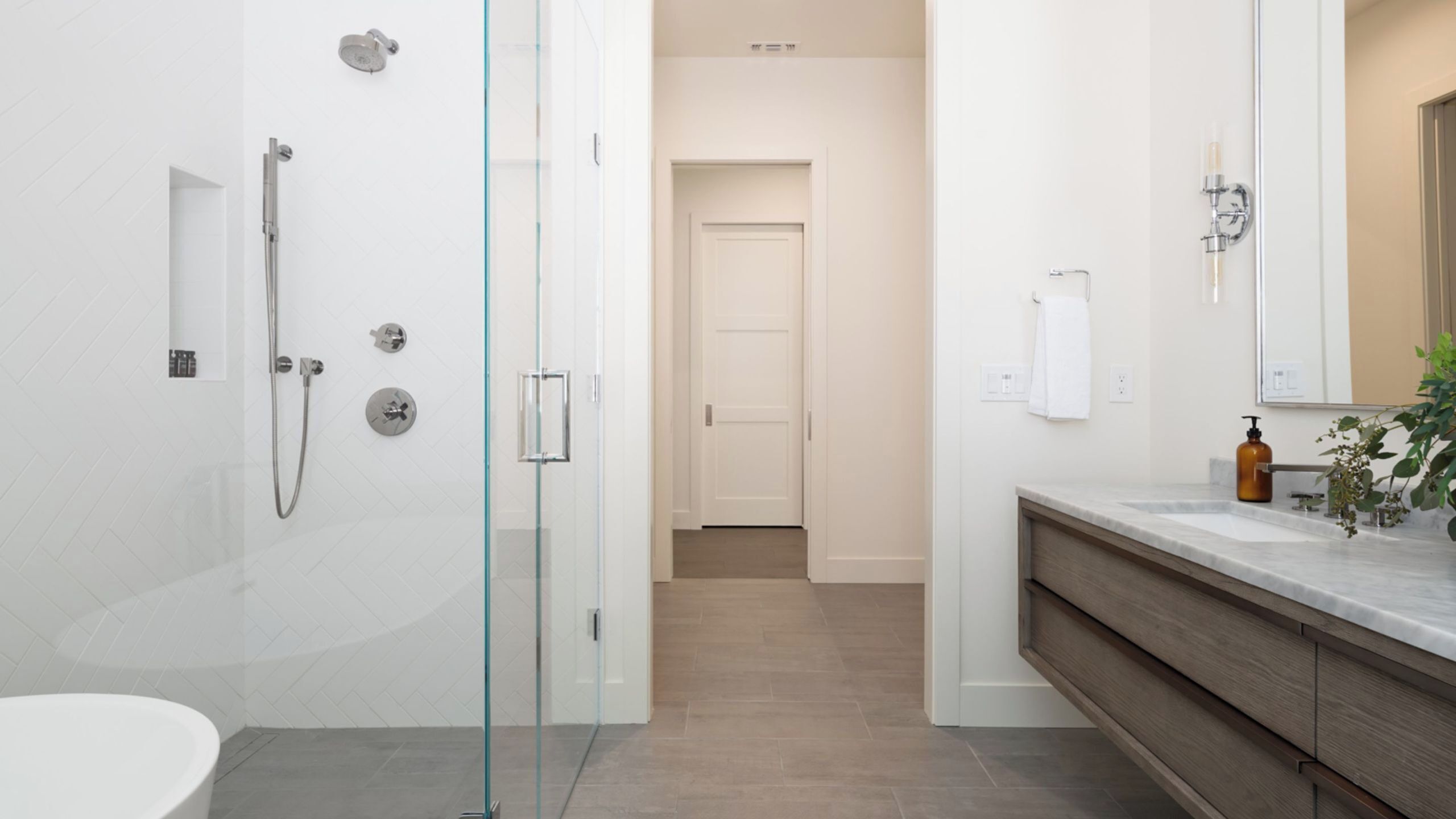 A modern bathroom with a glass shower enclosure, a white toilet, and a vanity with a mirror.