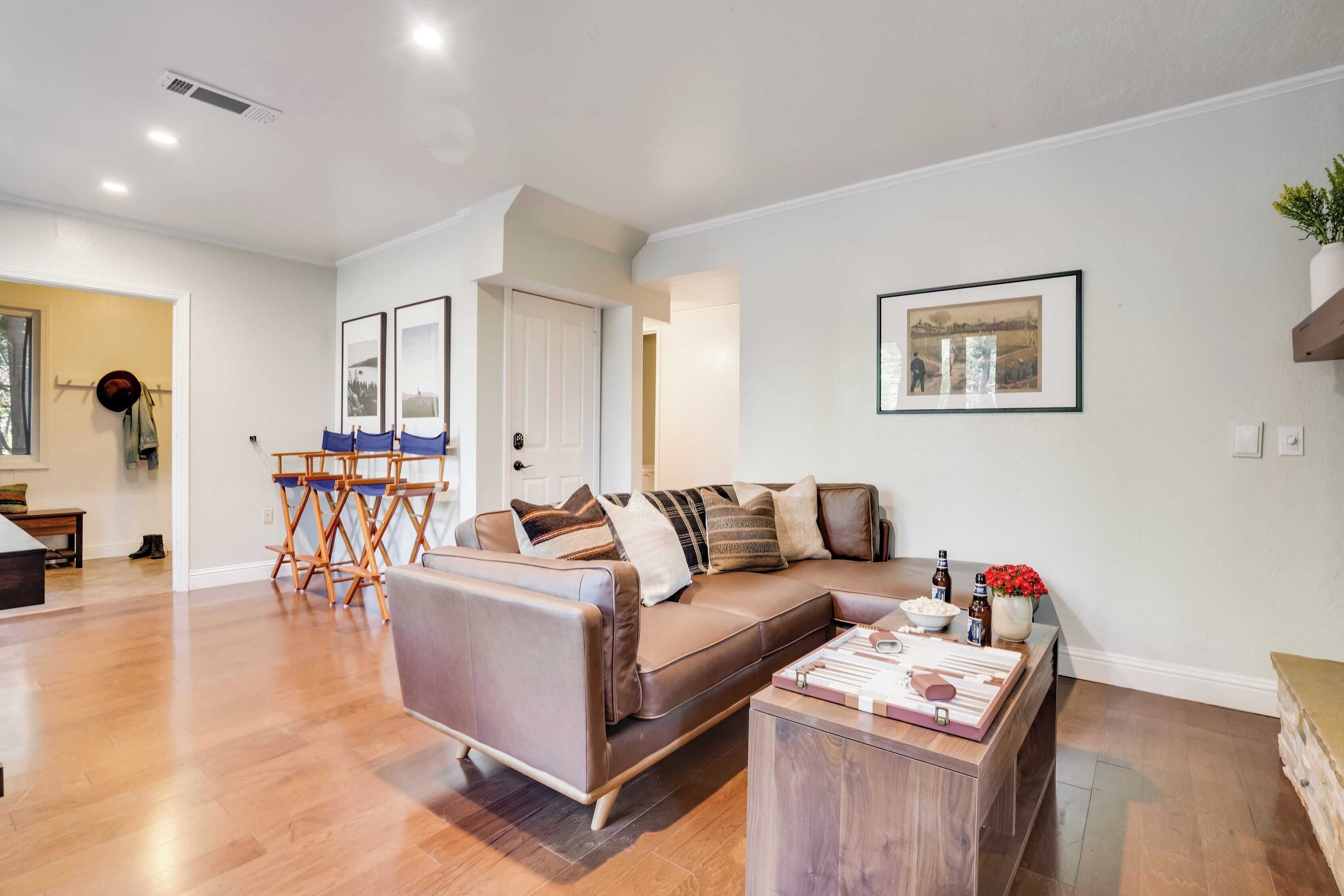 A modern living room with a brown leather sofa, wooden coffee table, and a framed picture on the wall.