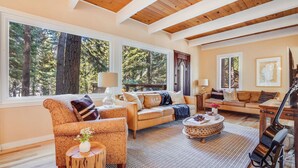 A spacious living room with large windows, a wooden ceiling, and a cozy seating area. - Hot Tub, Sauna, Game Room Modern 5bdr Family Cabin Homewood by Avantstay (Homewood)