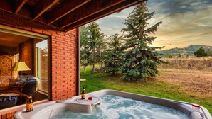 A hot tub with two glasses and a bottle, a brick wall, and a view of trees and hills. - Picasso by Avantstay Artist's Mountain Escape w/ Hot Tub & Views (Park City)