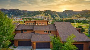 A residential area with multiple houses, a large building in the background, and a mountainous landscape. - Picasso by Avantstay Artist's Mountain Escape w/ Hot Tub & Views (Park City)