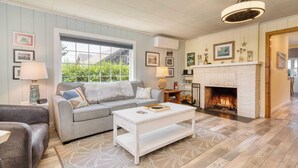A living room with a fireplace, a sofa, a coffee table, and a rug. - Beach Pines Bungalow by Avantstay Classic Cottage Steps to the Beach w/ Private Yard (Arch Cape)