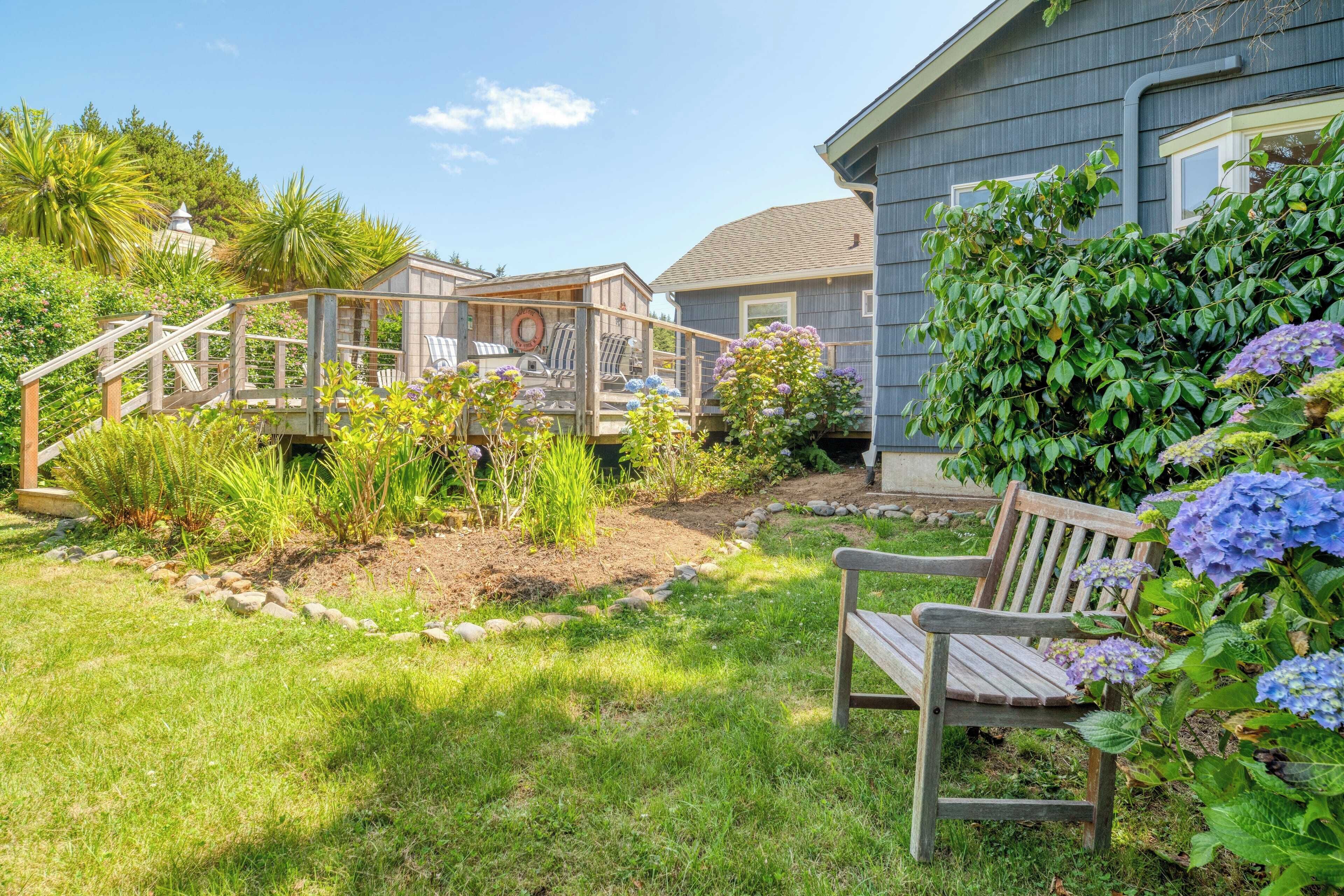 A backyard with a wooden deck, a bench, and a house with a grey exterior.
