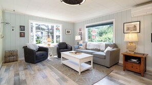 Ein Wohnzimmer mit Sofa, Sessel, Couchtisch und einem Beistelltisch mit Lampe.