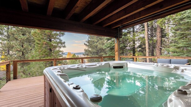 A hot tub on a wooden deck with a view of trees and a distant landscape.
