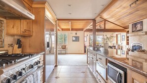 A spacious kitchen with wooden cabinets, a stainless steel refrigerator, a gas stove, and a built-in oven.