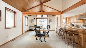 A spacious kitchen with wooden beams, a dining area with a table and chairs, and a large island with bar stools.