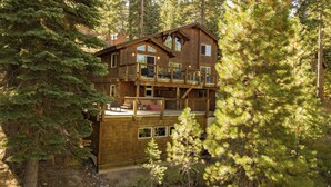 A multi-story wooden cabin surrounded by dense forest.