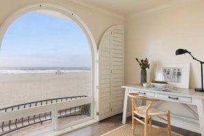 Ein Zimmer mit Schreibtisch, Stuhl und Blick auf den Strand.
