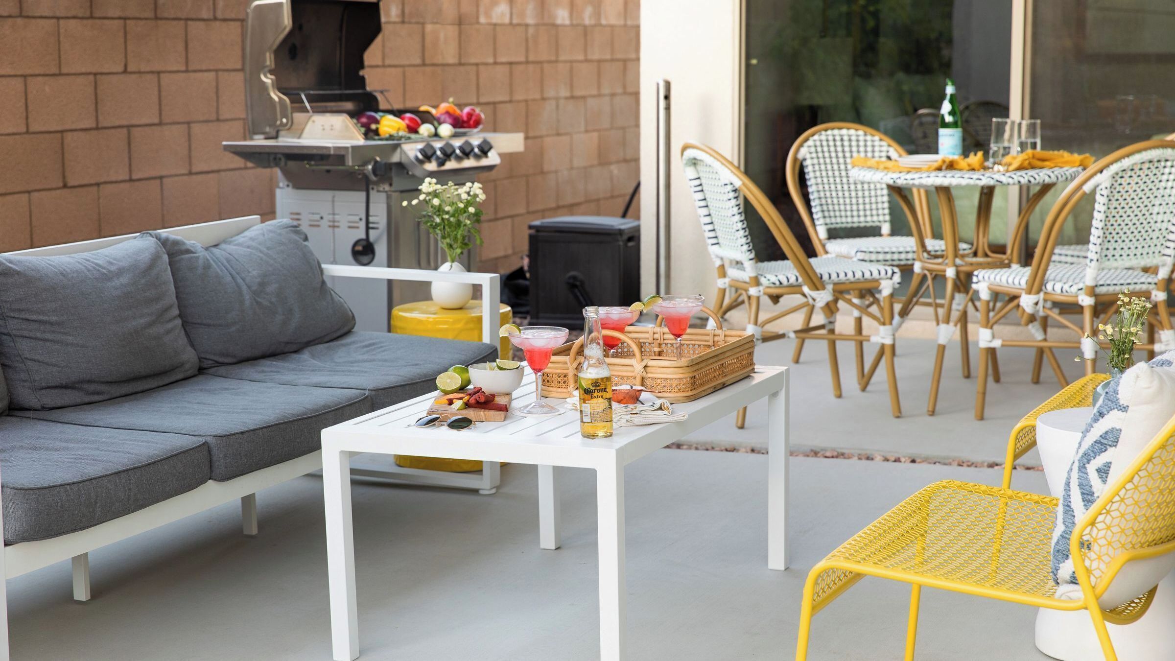 An outdoor patio with a sofa, dining table, chairs, and a barbecue grill.