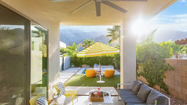 A patio with a yellow-striped umbrella, outdoor furniture, and a view of mountains. - Marilyn by Avantstay Mins to Old Town La Quinta! (La Quinta)