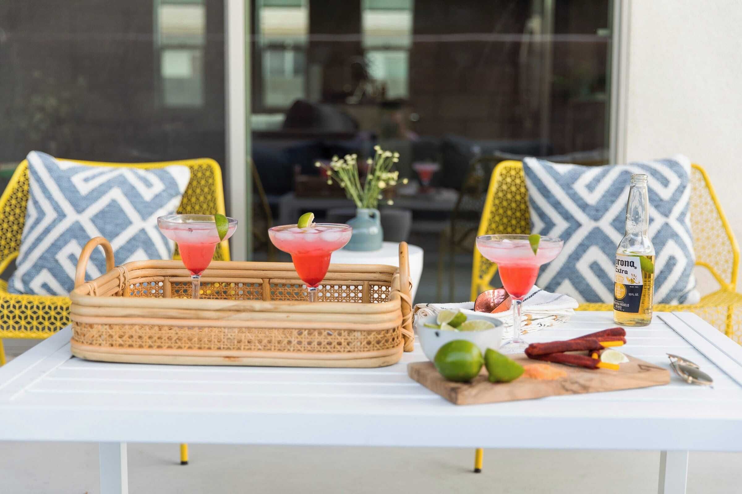 Une table dressée avec deux boissons, une bouteille de Corona et un bol de tranches de citron vert.
