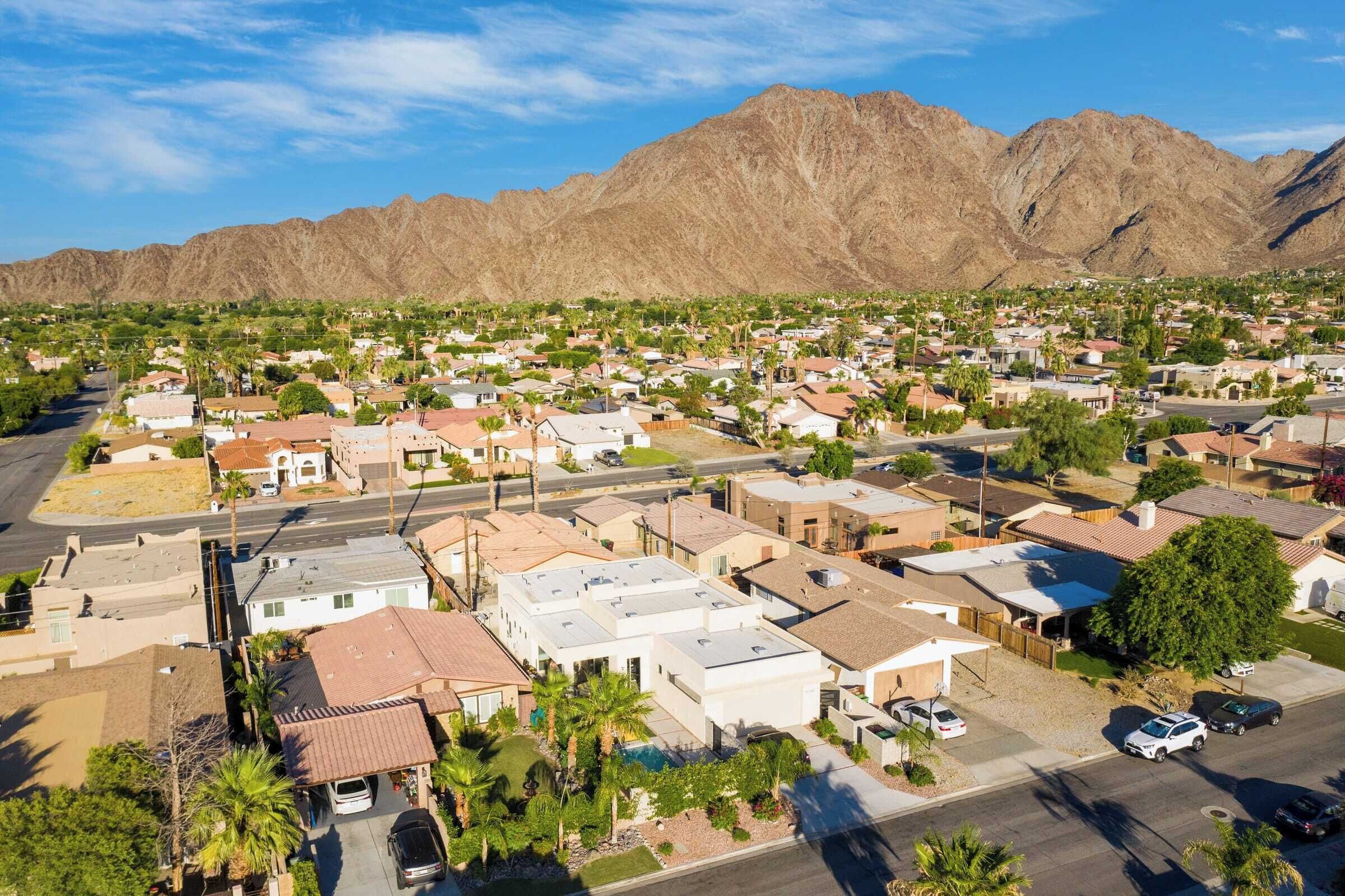 Un quartier résidentiel avec des maisons, une rue et des montagnes en arrière-plan.
