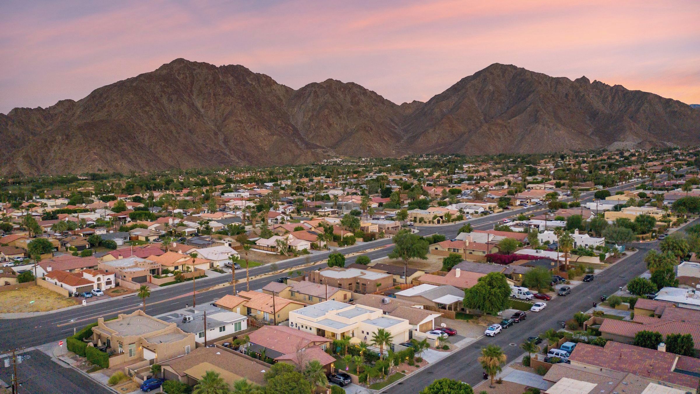 A residential area with houses, roads, and mountains in the background.