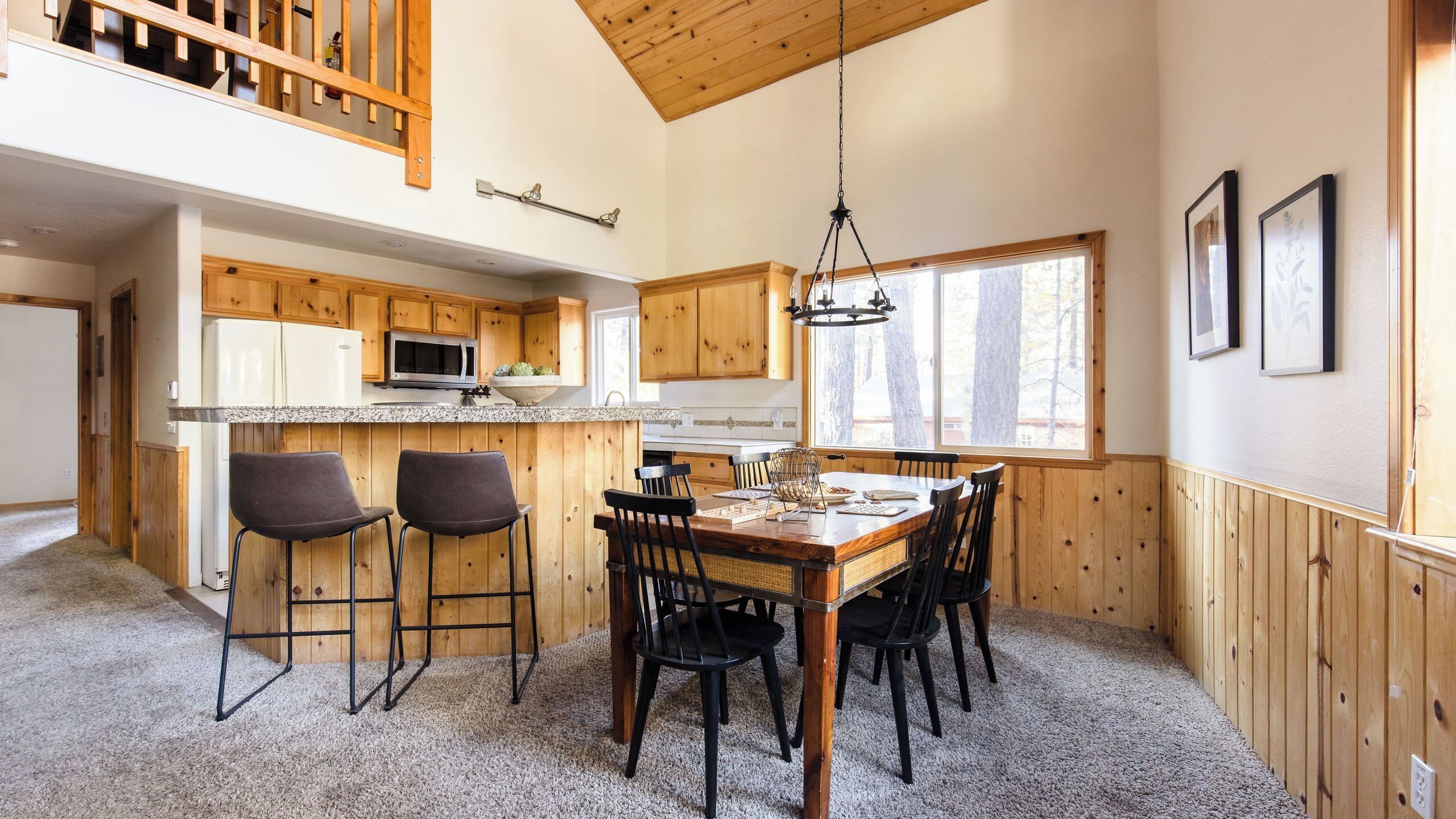 A kitchen with wooden cabinets, a microwave, and a dining area with a table and chairs.