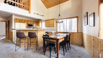 A kitchen with wooden cabinets, a microwave, and a dining area with a table and chairs.