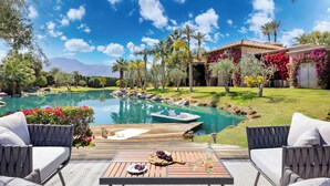 A poolside area with outdoor seating, a boat, and a view of a mountain.