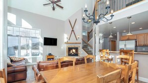 A spacious living room with a fireplace, wooden dining table, and leather sofa.
