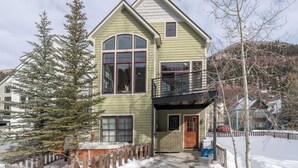 A two-story house with a balcony, a large window, and a wooden fence.