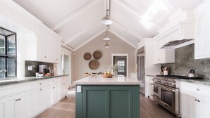 Una cocina amplia con armarios blancos, una isla central y una cocina grande.