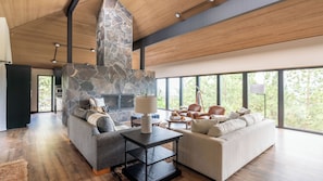 Amplia sala de estar con chimenea de piedra, ventanas grandes y muebles modernos.