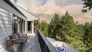 A wooden deck with a sofa and a table, overlooking a forested area.