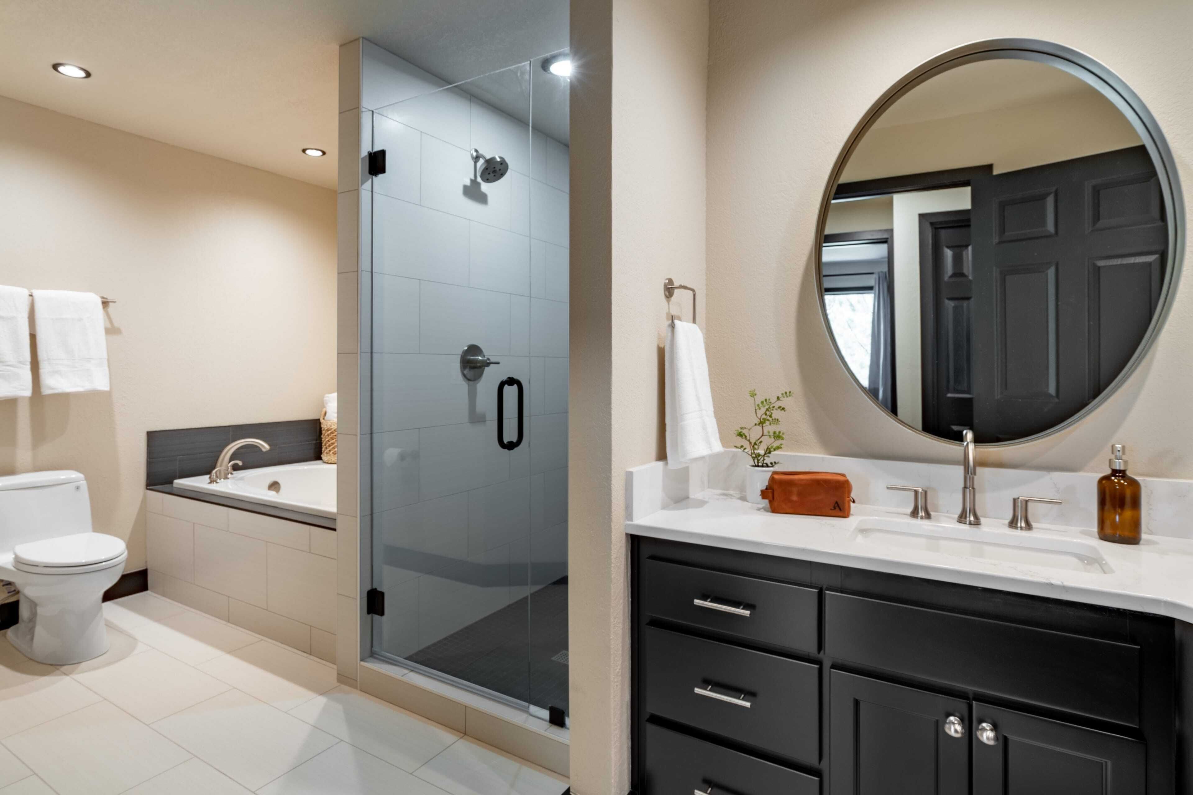 A modern bathroom with a glass-enclosed shower, a toilet, a sink, and a vanity with drawers and a mirror.