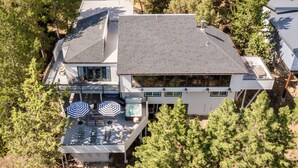 A two-story house with a large deck, outdoor seating, and a hot tub.