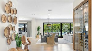 Un intérieur moderne comprenant un coin repas, un meuble à vin et une vue sur l’extérieur.