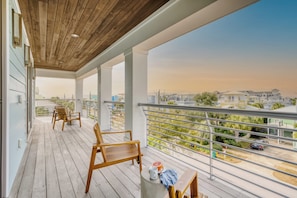 Ein Balkon mit Holzboden, weißen Geländern und Blick auf ein Wohngebiet.