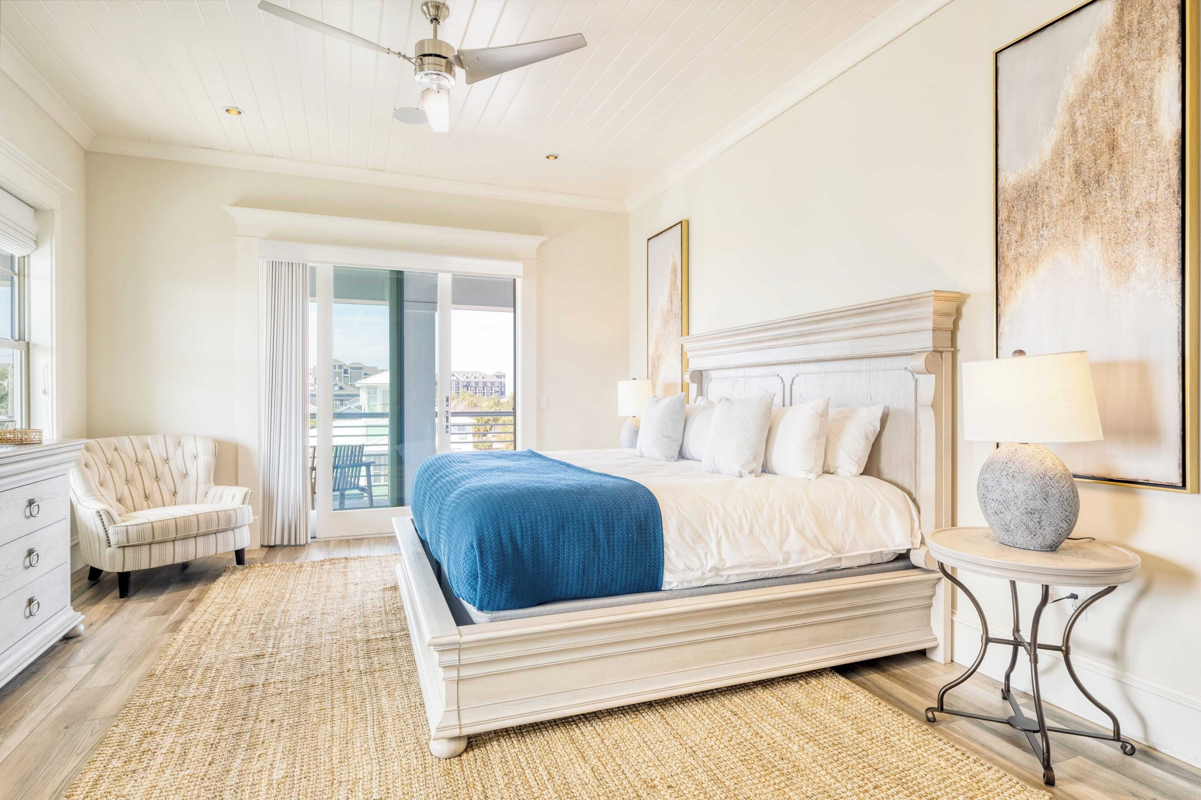 A bedroom with a large bed, a chair, a dresser, and a view of the outdoors.