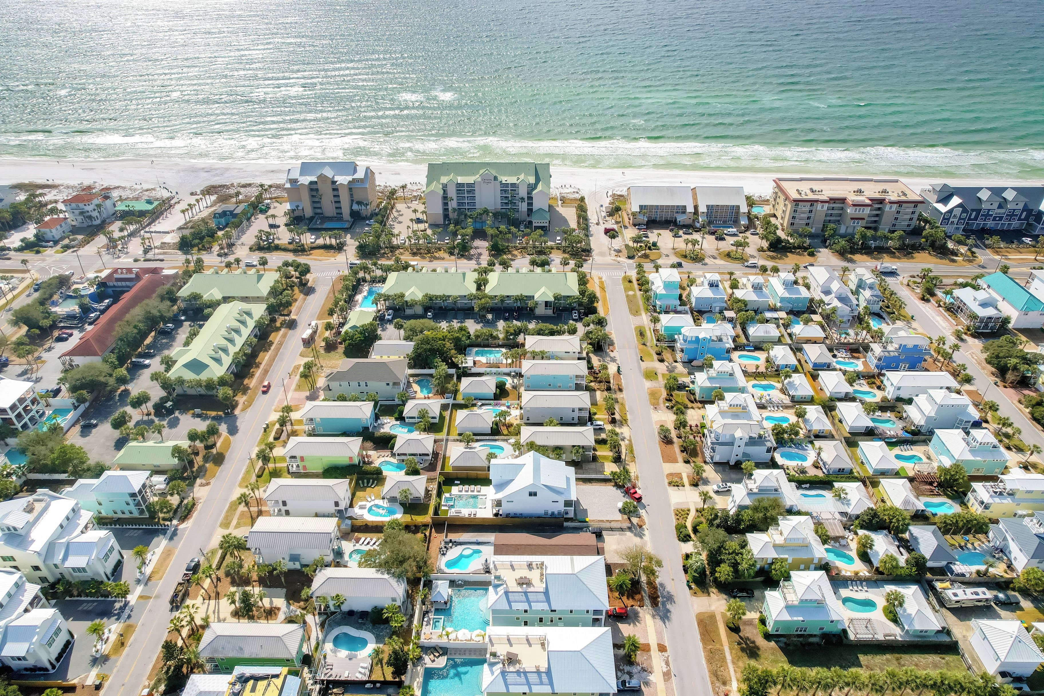 An aerial view of a coastal resort with multiple buildings, swimming pools, and a beach.