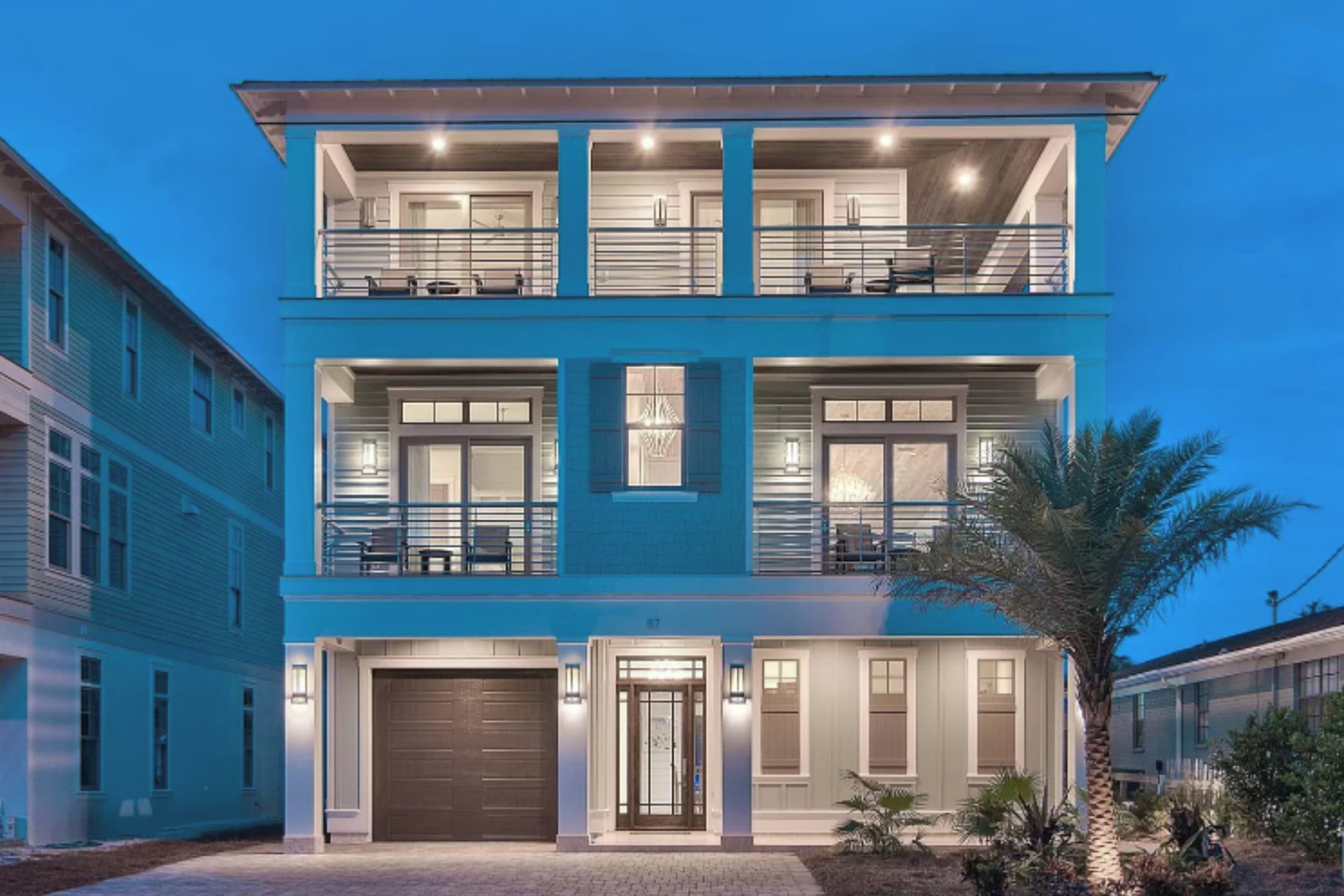 Una casa moderna a due piani con garage, ampie finestre e un balcone.