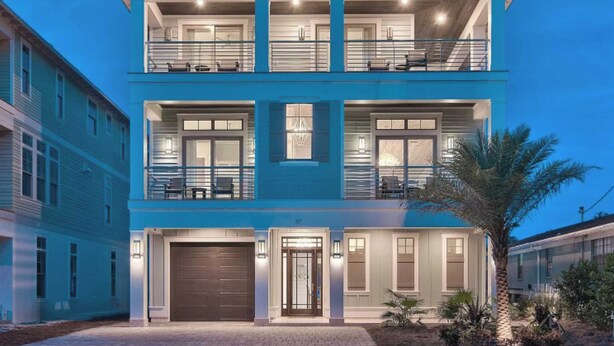 A two-story modern house with a garage, large windows, and a balcony. - Monarch by Avantstay Stunning Estate 1 Block to Beach, Swim Up Bar, Hot Tub, & Rooftop Views (Destin)