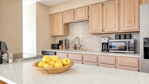 A modern kitchen with wooden cabinets, a marble countertop, a coffee maker, a toaster, and a bowl of lemons. - Cloud 9 by Avantstay Located at the Base of Vail Ski Resort w/ Community Pool & Hot Tub (Vail)