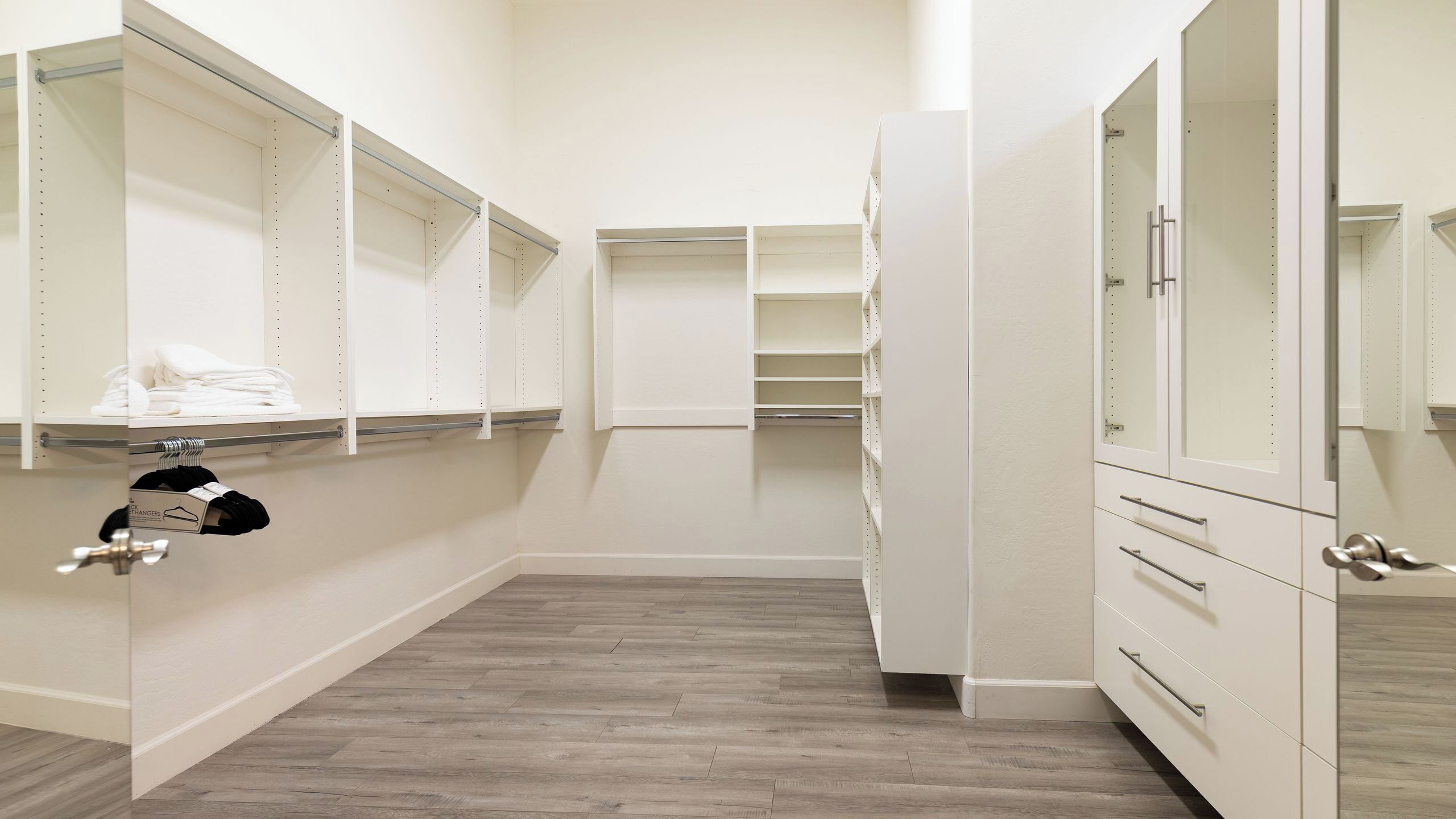 A walk-in closet with open shelves, a hanging rod, and a mirrored wardrobe.