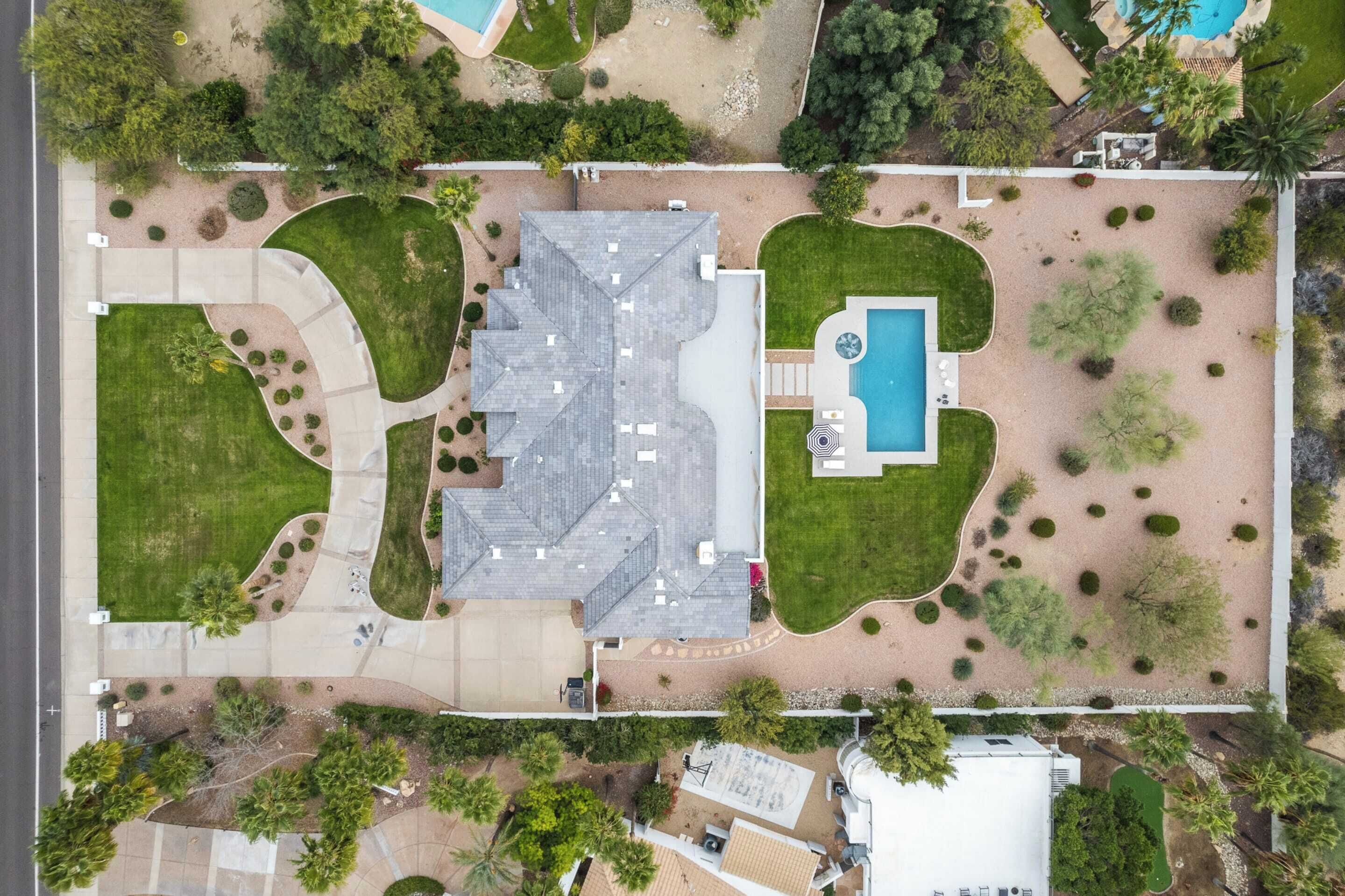 An aerial view of a residential property with a large house, a swimming pool, and landscaped gardens.