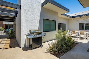 Enjoy al fresco dining and relaxation in this patio area, featuring a barbecue grill, seating and a lush garden.