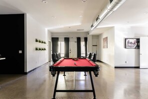 Relax in this stylish room with a pool table, comfortable seating, and a large painting on the wall.